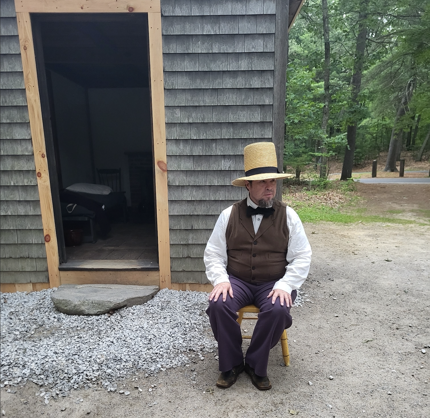 Man sitting on a stool in old-fashioned attire.